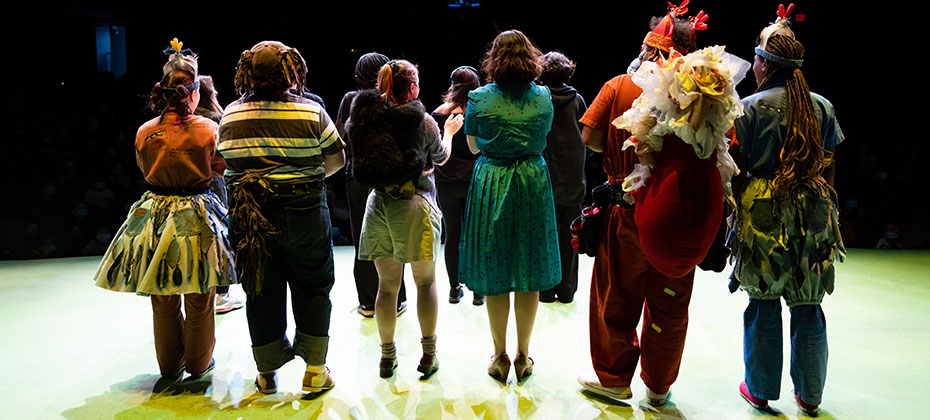 photo from backstage of actors on stage facing audience